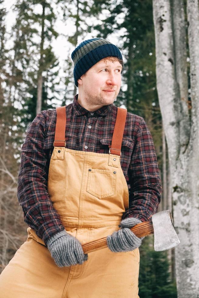 Portrait of a man lumberjack with an ax in his hands on a background of forest and trees photo