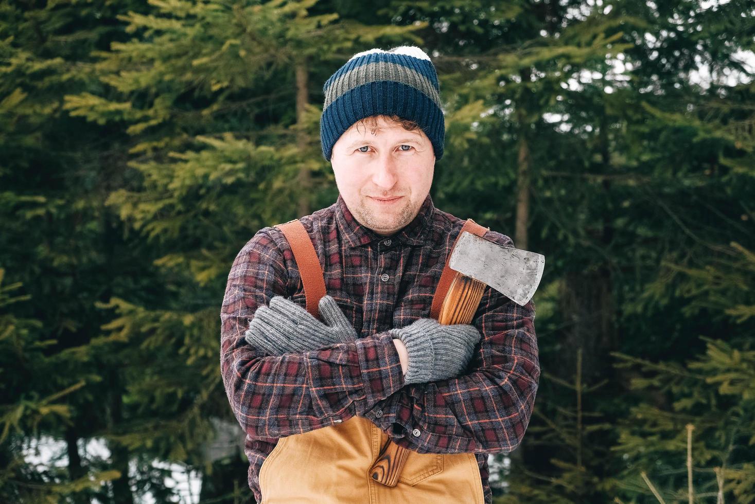 Portrait of a man lumberjack with an ax in his hands on a background of forest and trees photo