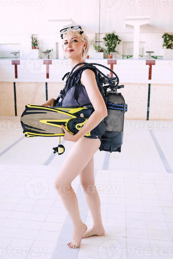 young blonde woman with diving equipment in empty swimming pool. Education, hobby concept photo
