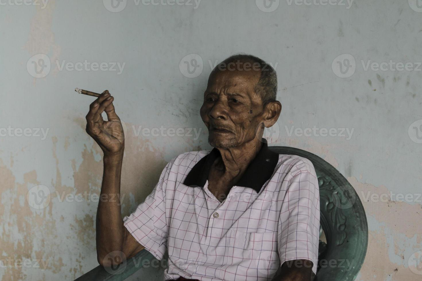 Close up portrait of Asian Javanese old man with a cigarette in his hand photo