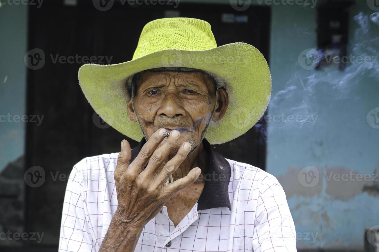 Close up portrait of Asian Javanese old man with a cigarette in his hand photo