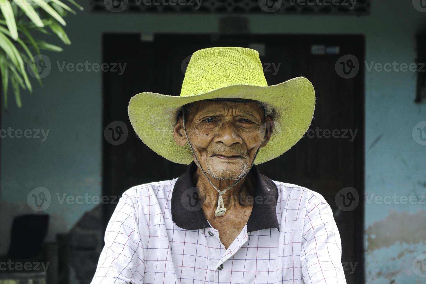 A portrait of Indonesian old farmer wear yellow hat with old bicycle photo