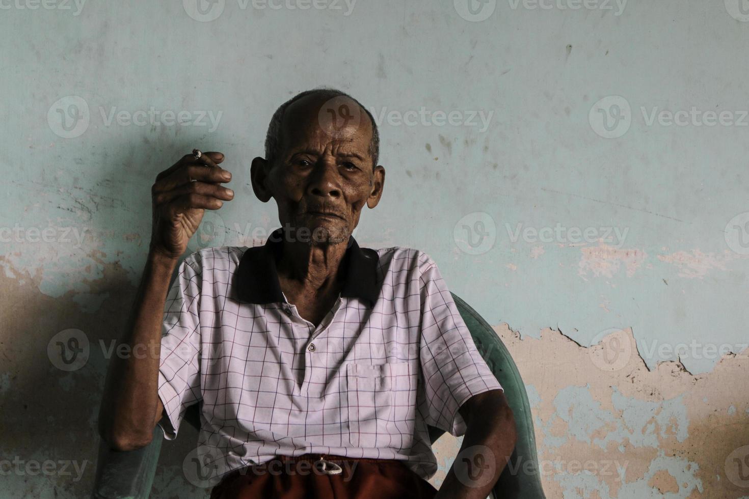 Close up portrait of Asian Javanese old man with a cigarette in his hand photo