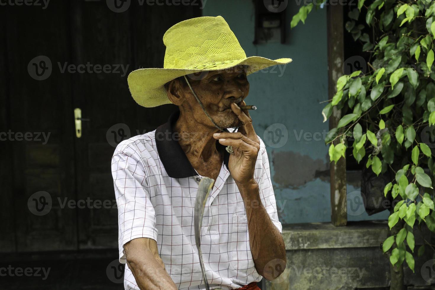 Close up portrait of Asian Javanese old man with a cigarette in his hand photo