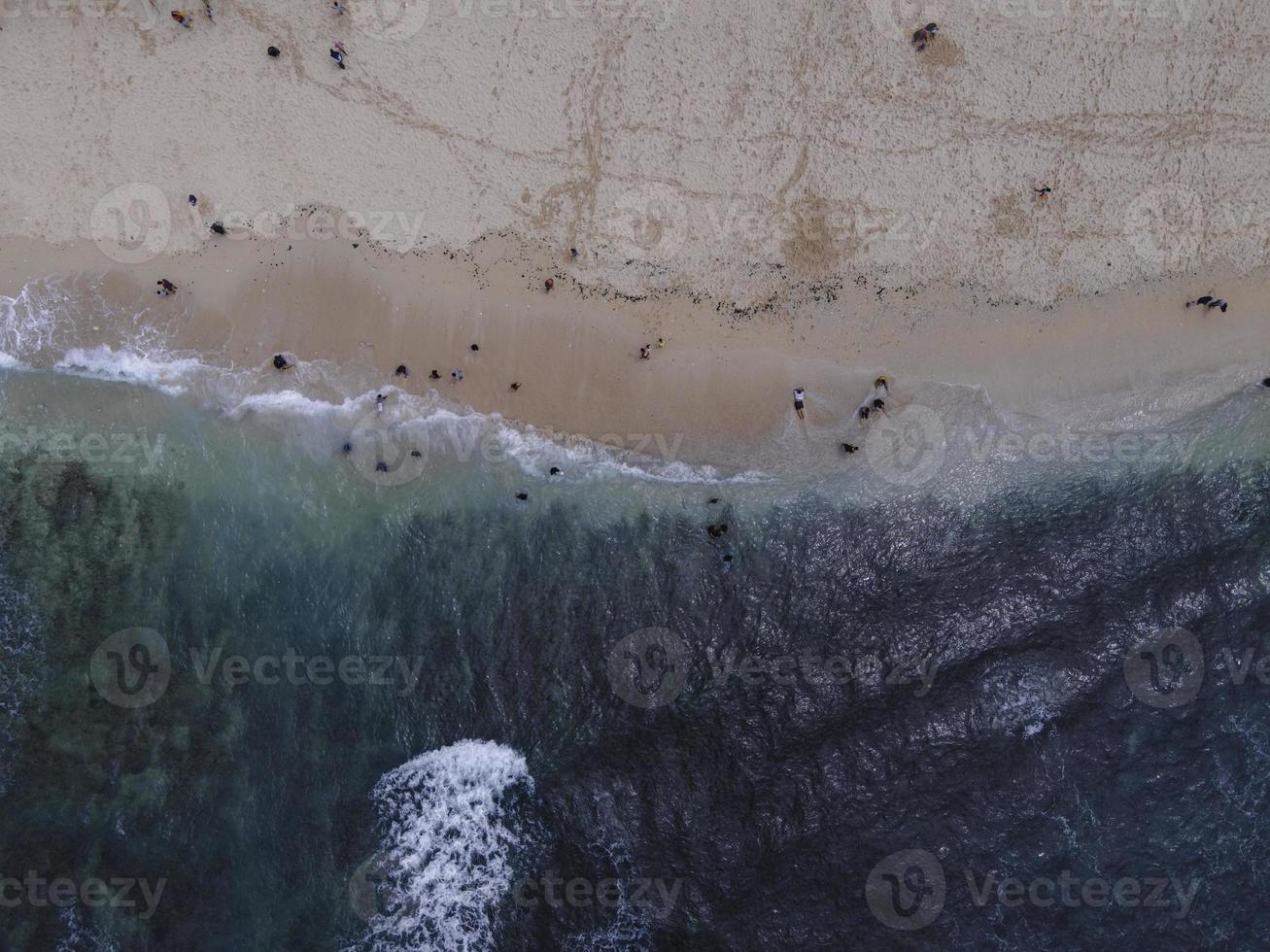 Aerial drone view of Holiday In Gunung Kidul Beach, Indonesia with ocean, boats, beach, and people. photo