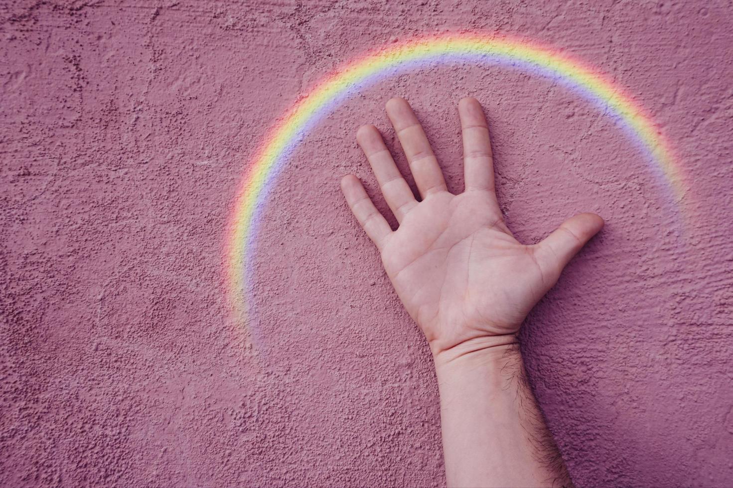 hand with a rainbow on the pink wall. lgbt symbol photo