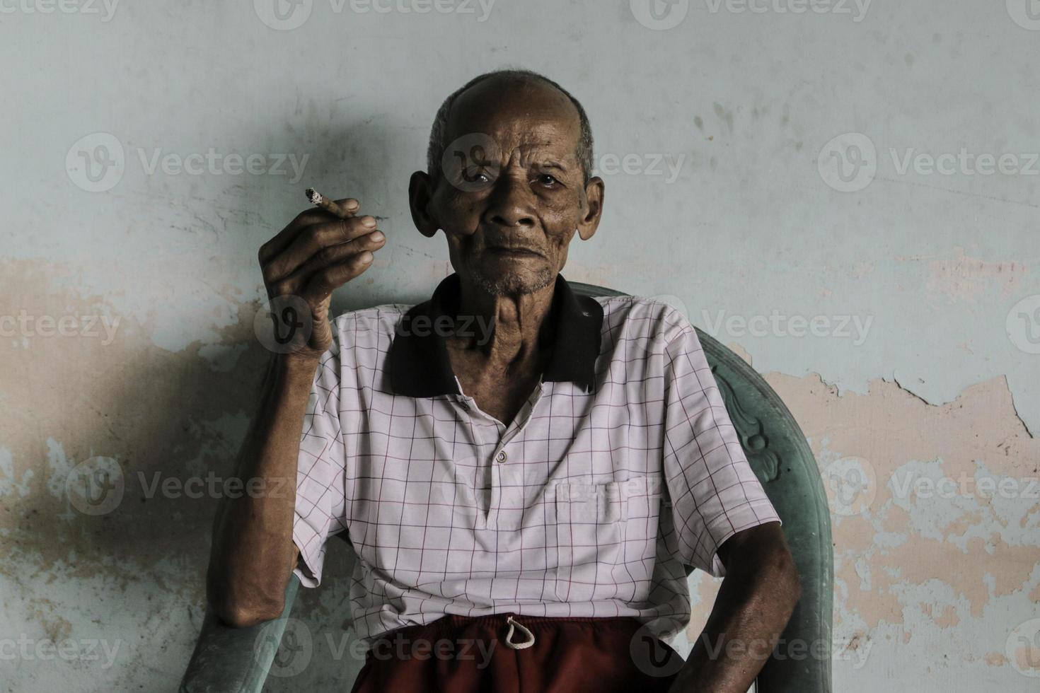 Close up portrait of Asian Javanese old man with a cigarette in his hand photo