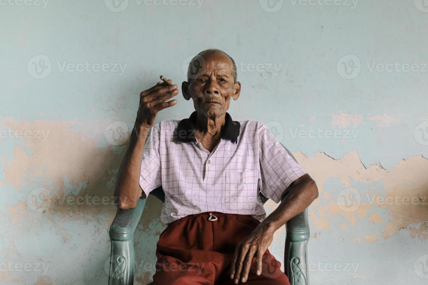 Close up portrait of Asian Javanese old man with a cigarette in his hand photo