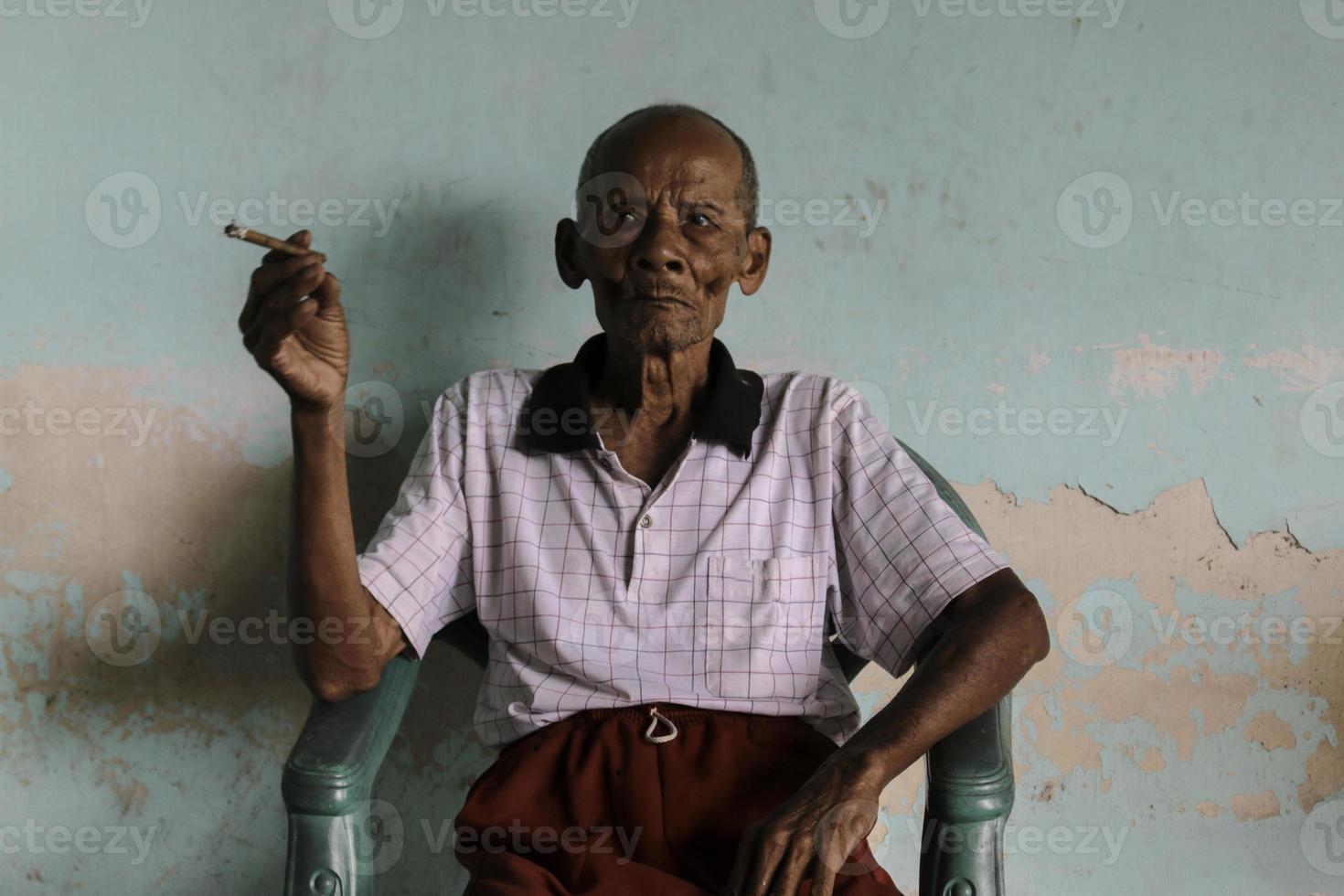 Close up portrait of Asian Javanese old man with a cigarette in his hand photo