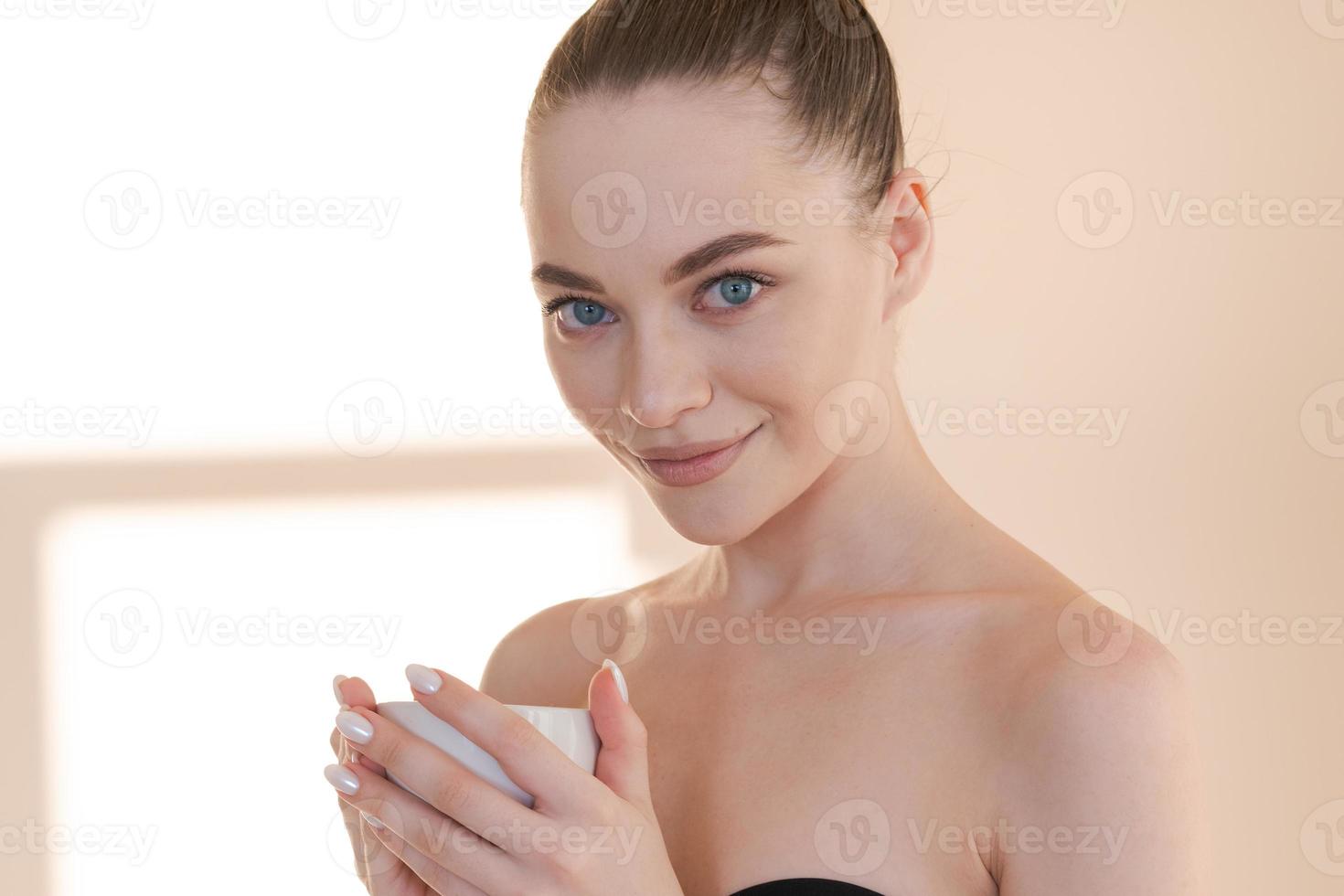 Beautiful girl with mug in her hand stands against background wall with rays photo