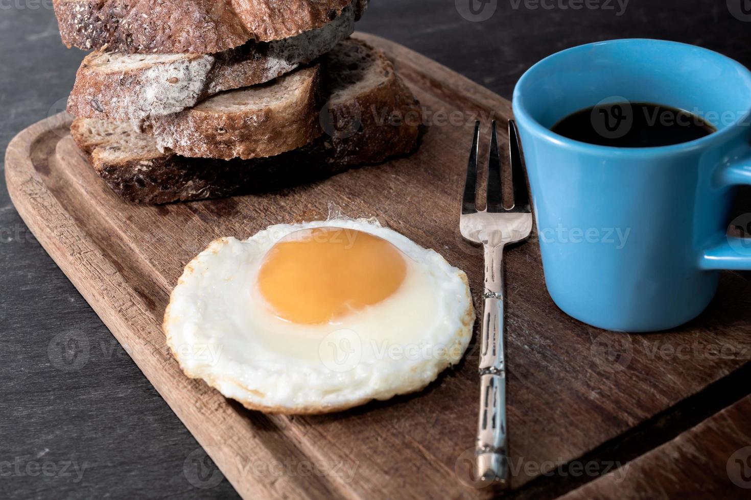 Breakfast food fried egg bread slice has espresso coffee in cutting board. photo