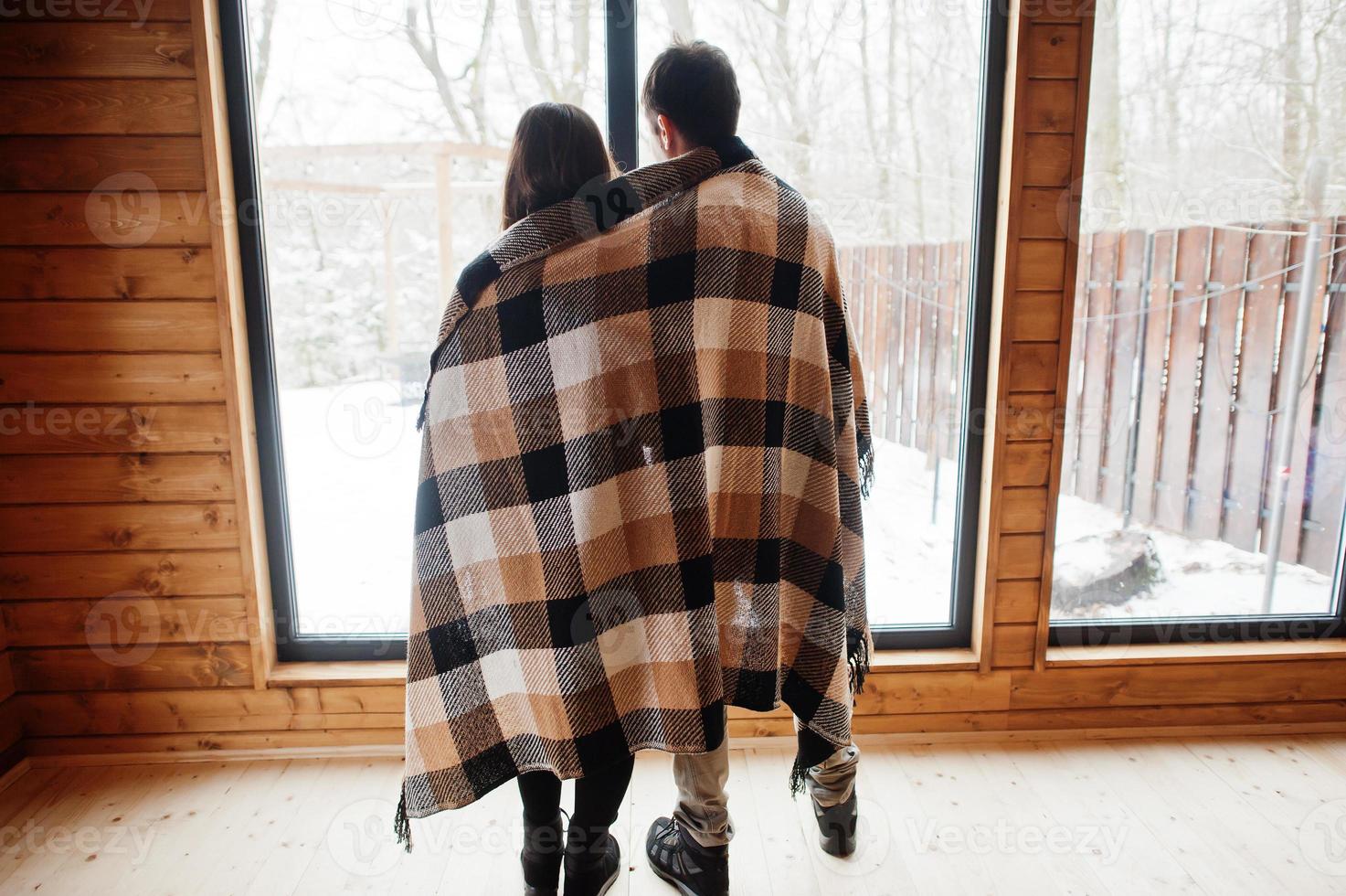 Couple covered blanket in modern wooden house spending time together in warm and love. photo