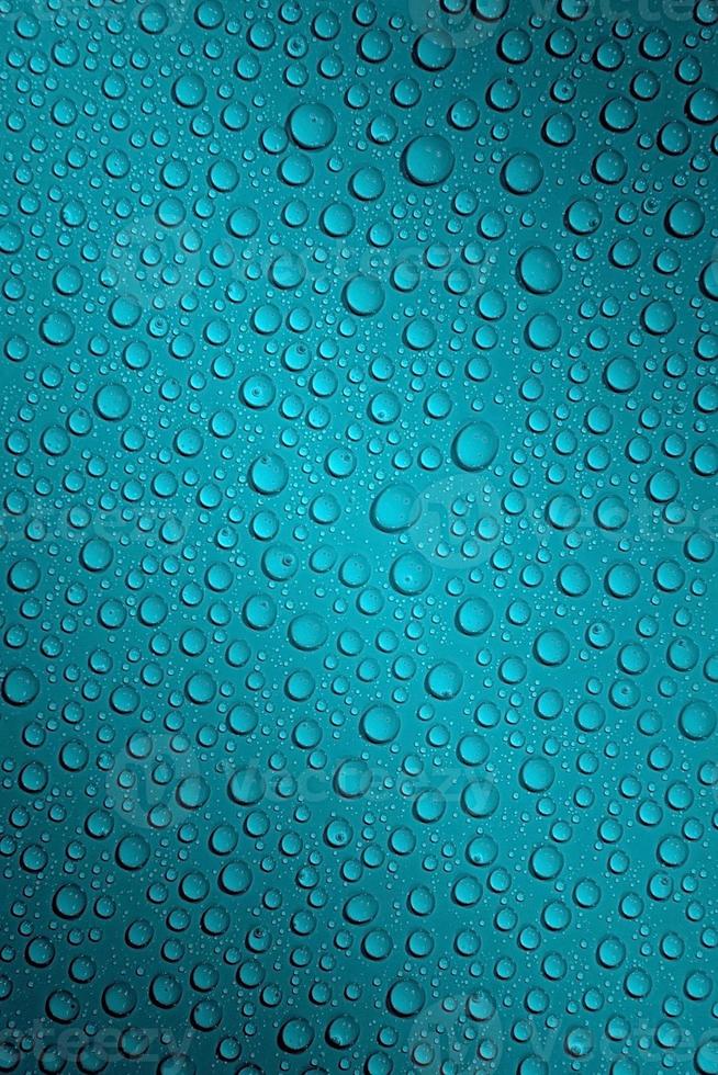 Wet with water drops dark turquoise background with gradient illumination at two corners, macro photo