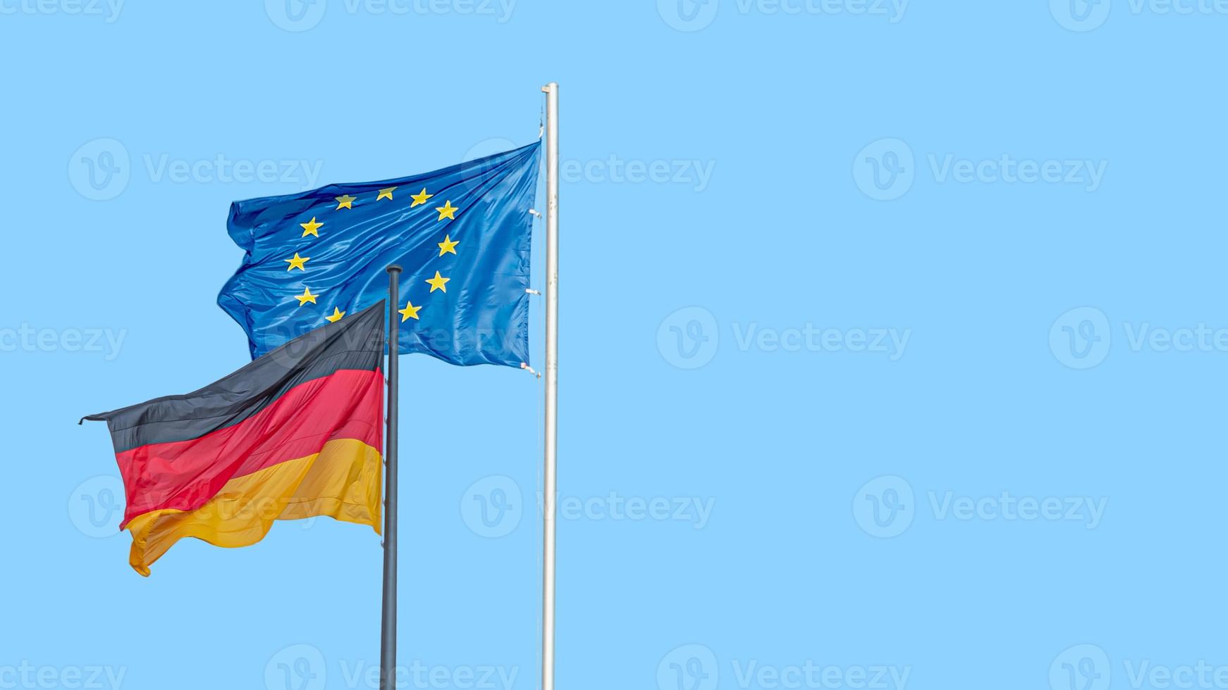 Banner with a national black red yellow flag of Germany and blue flag with stars of EU and at blue sky background with copy space, details, closeup. Concept of nationality, citizenship and patriotism. photo