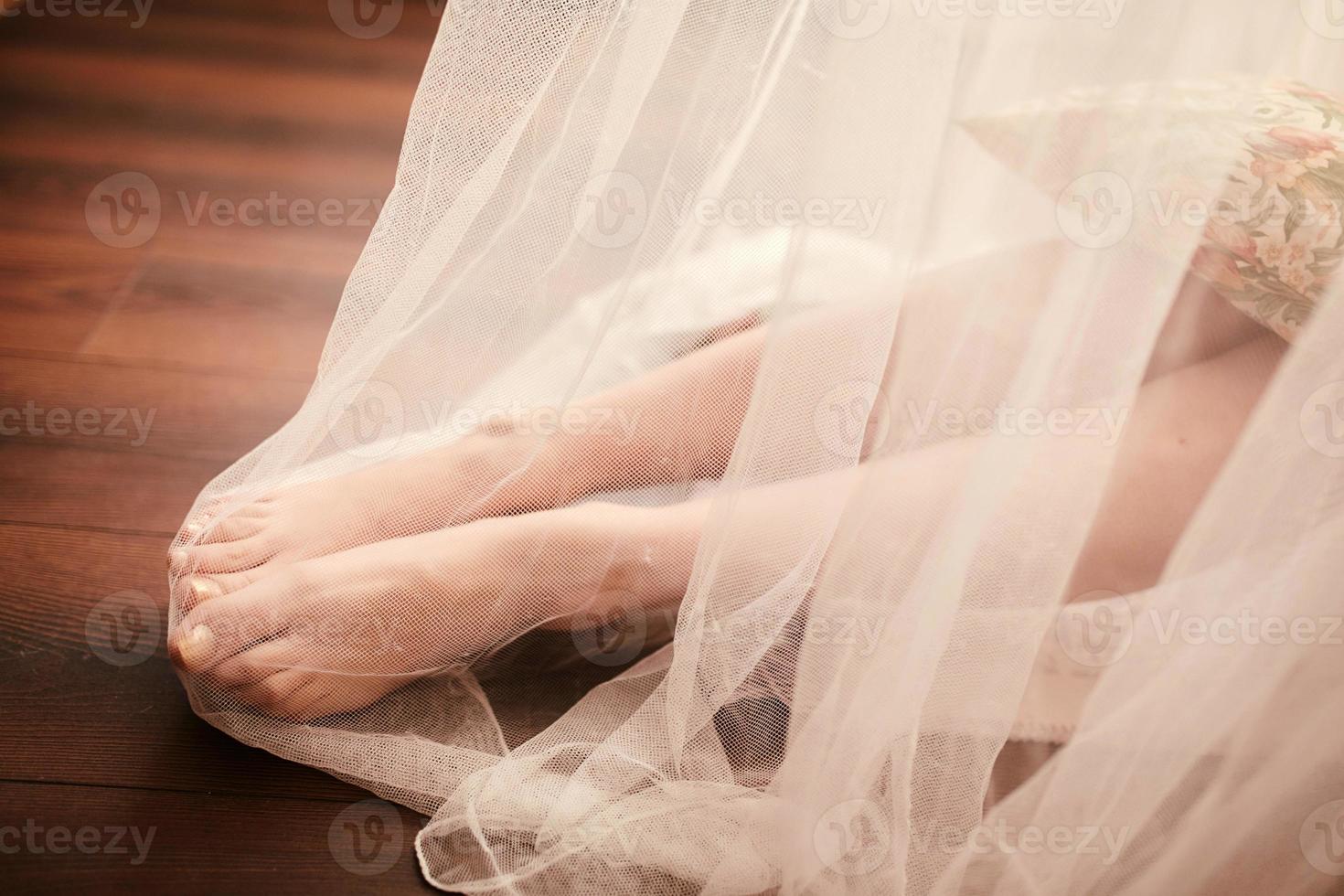 Bride morning preparation. Bride legs in white veil on wooden floor. photo