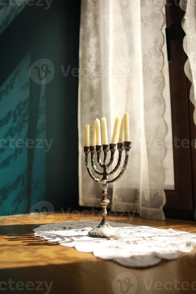 Candles in vintage copper candle holder on wooden table near the window in country house interior photo