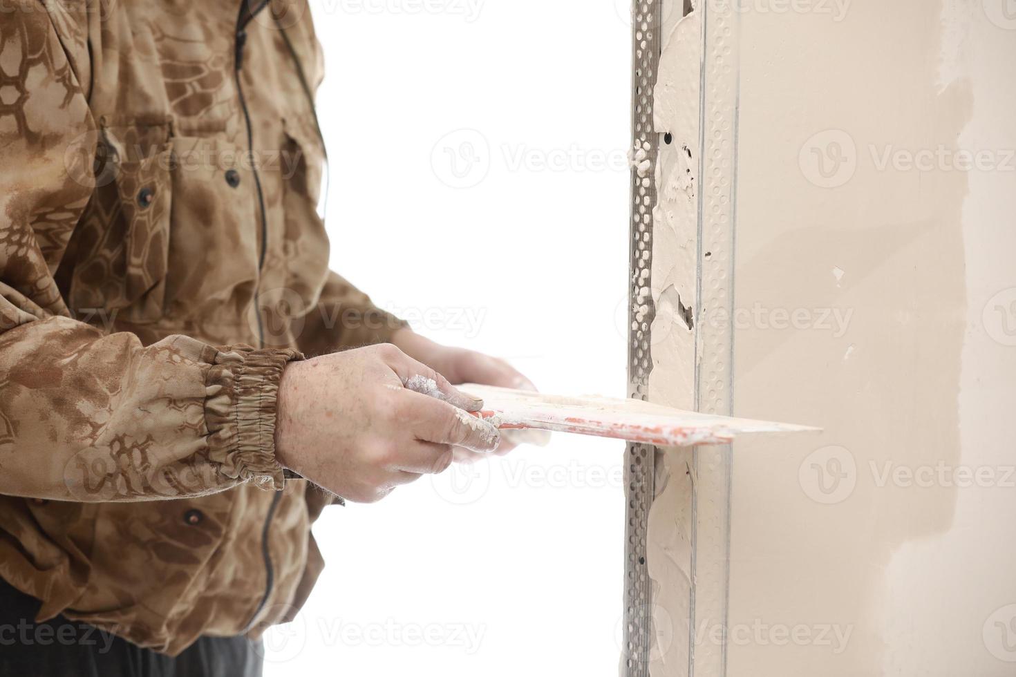 Builder using a trowel to add plaster. Plastering wall with putty-knife, close up image. Fixing wall surface and preparation for painting. construction work during quarantine photo