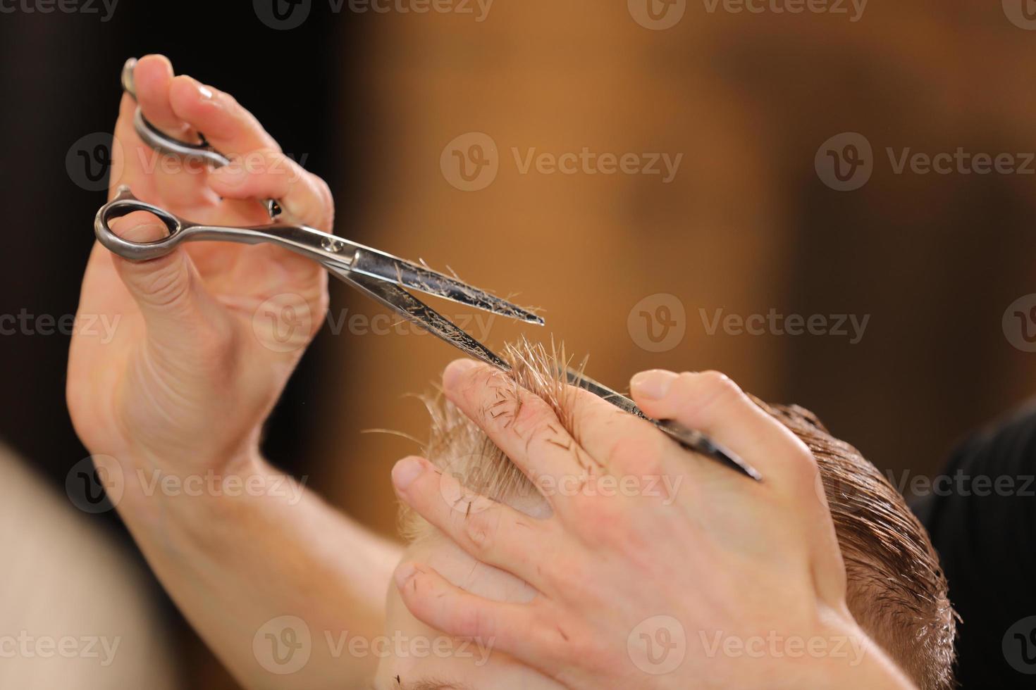 peluquería masculina, corte de pelo, en una barbería o peluquería. primer plano de las manos del hombre acicalando el cabello del niño en la peluquería. retrato de niño varón en la peluquería para cortarse el pelo. foto