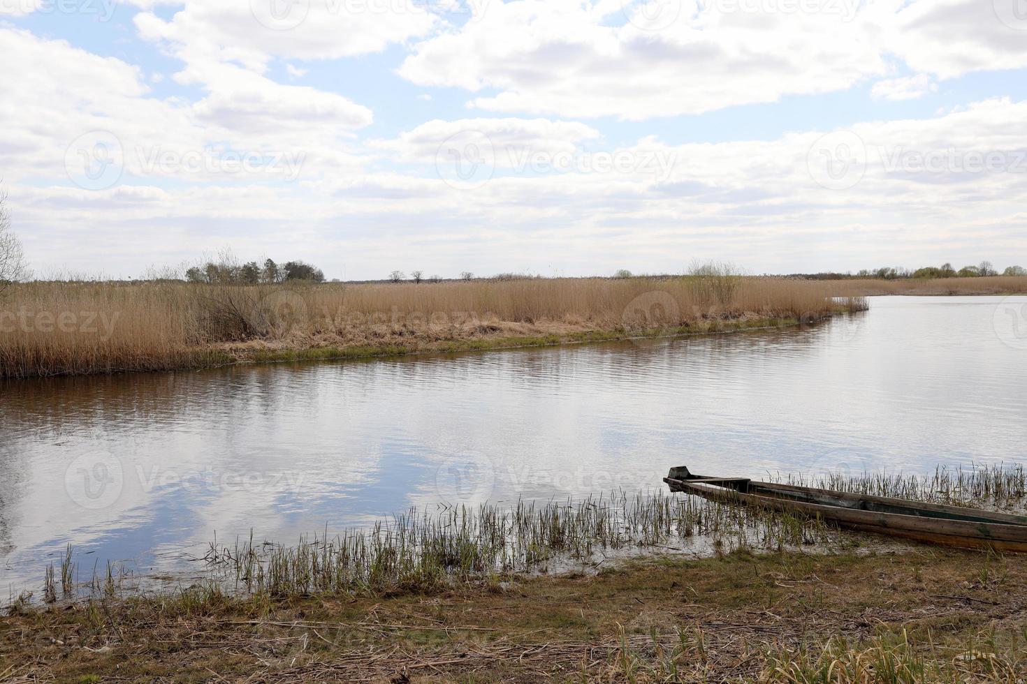 Old wooden fishing boat near the summer lake shore. photo