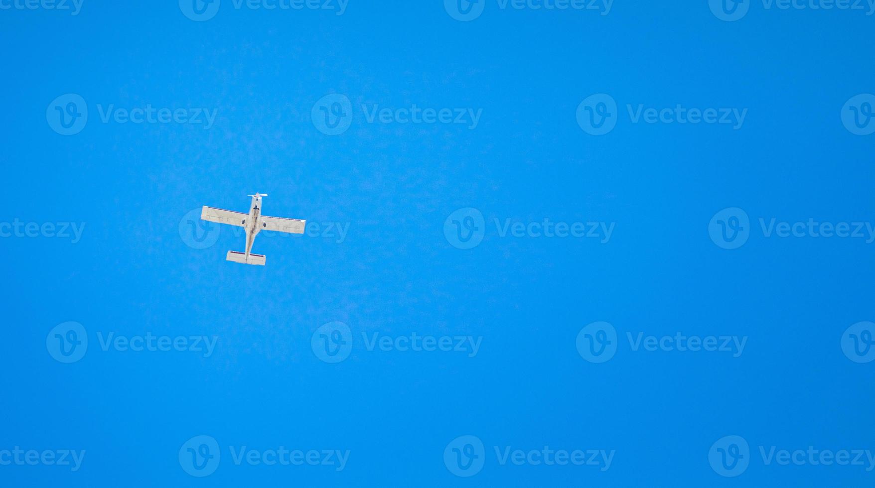 A small light plane flies in the clear sky. View from below. Horizontal orientation. photo