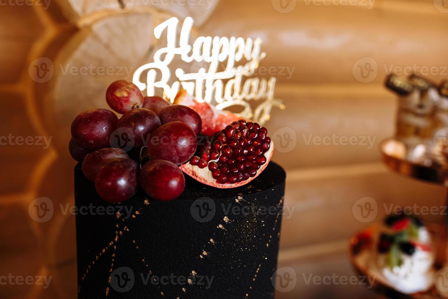 big black birthday cake with fresh fruits and sweets on a festive table. Candy bar. Table with different sweets for party photo