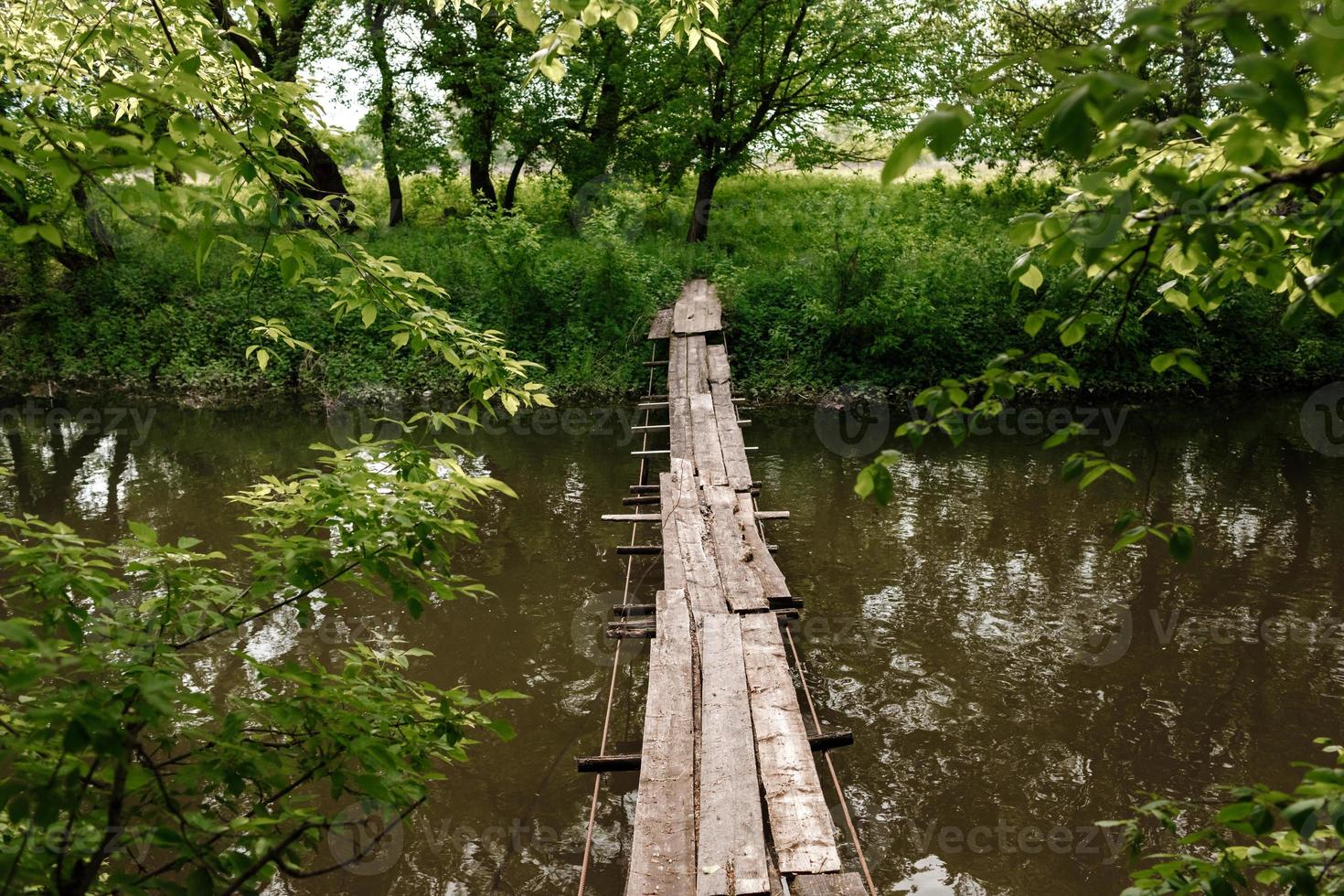 A small wooden bridge over a mild stream in a green park. photo