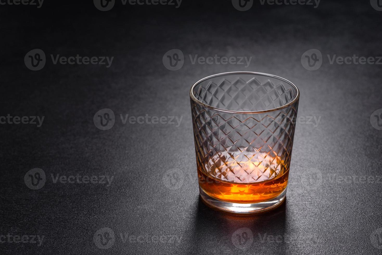 A glass of whiskey or cognac on a black concrete table. Relaxation time photo