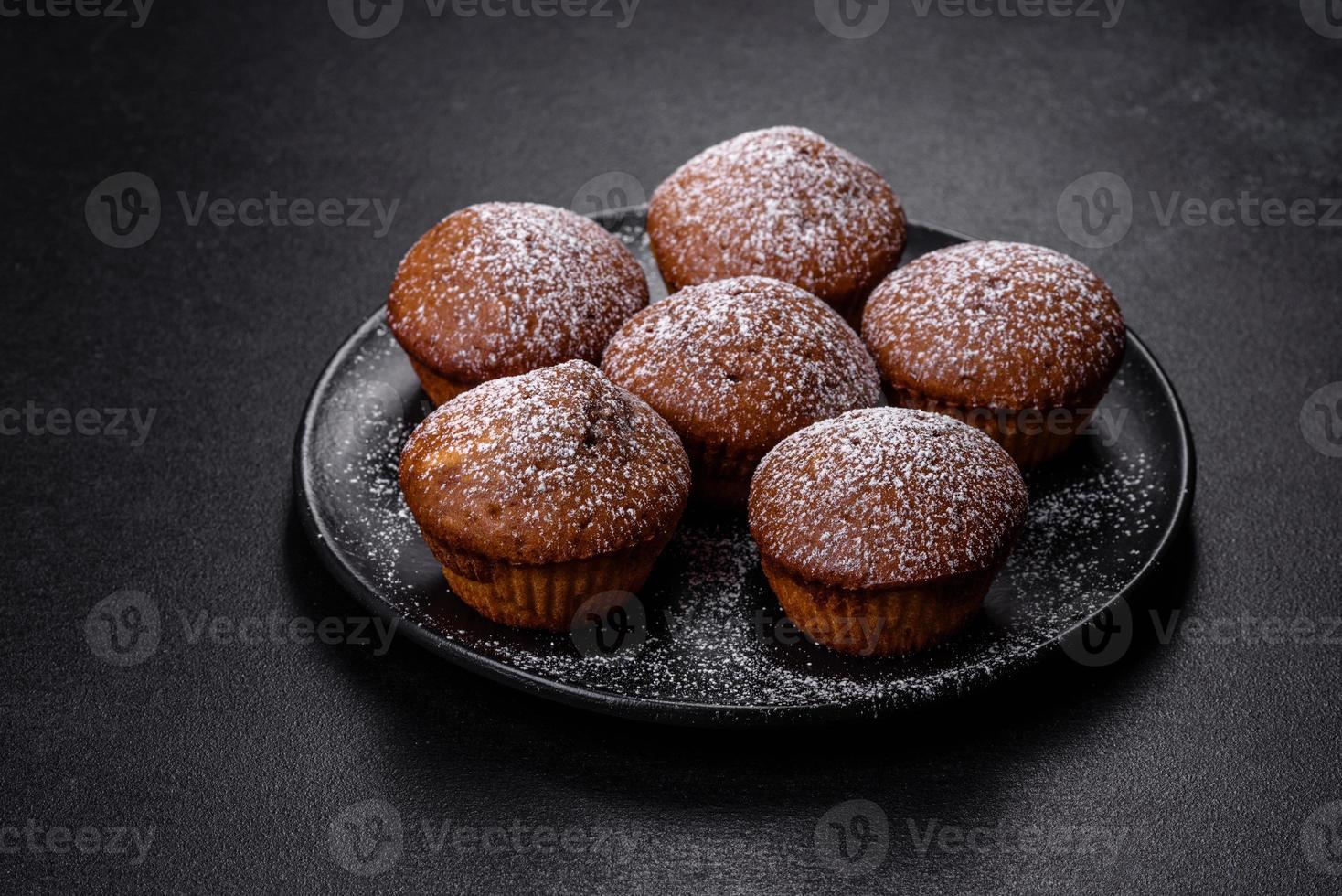 Beautiful delicious cupcakes with cocoa and raisins on a black concrete background photo