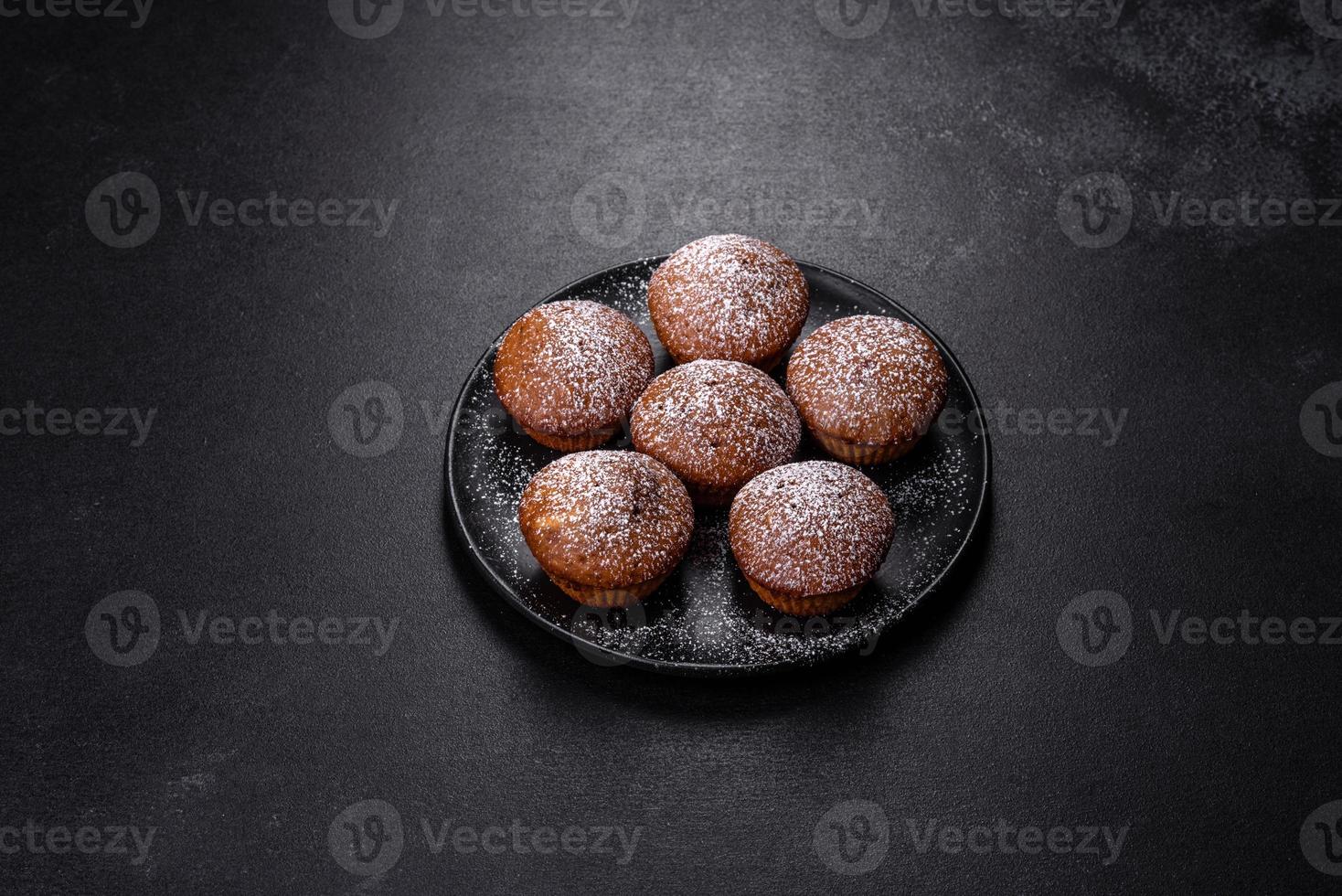 Beautiful delicious cupcakes with cocoa and raisins on a black concrete background photo