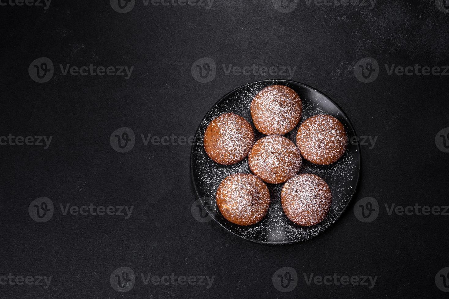 Beautiful delicious cupcakes with cocoa and raisins on a black concrete background photo