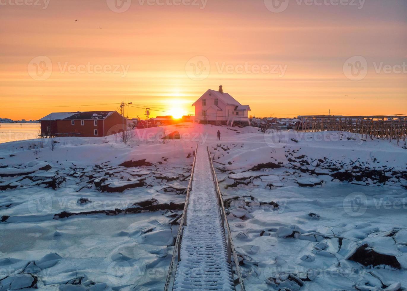 amanecer sobre la casa nórdica y el puente de madera en la costa en invierno en las islas lofoten foto