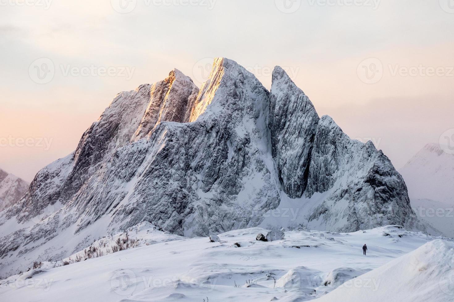 Majestic snowy mountain with mountaineer on snow hill at sunrise photo