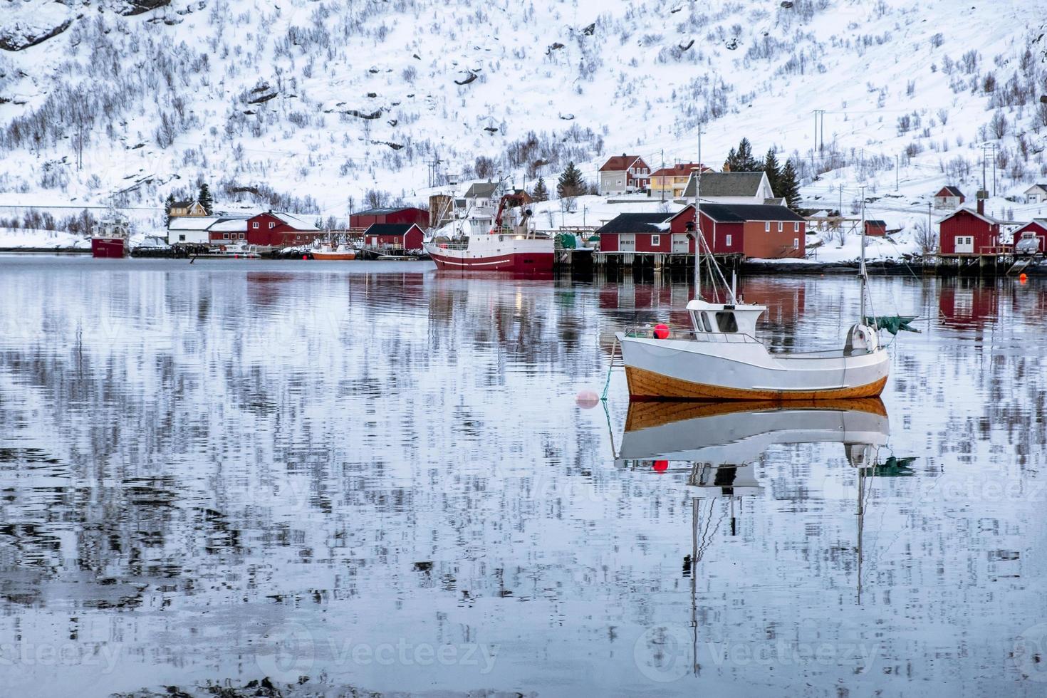 Fishing boat floating and reflection on seashore in scandinavian village photo