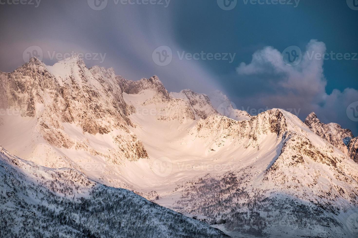 Golden sunrise on snow mountain with clouds blowing on ridge photo