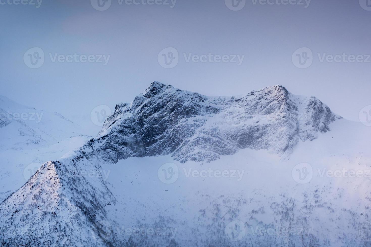 Snowy mountain peak with light in foggy photo