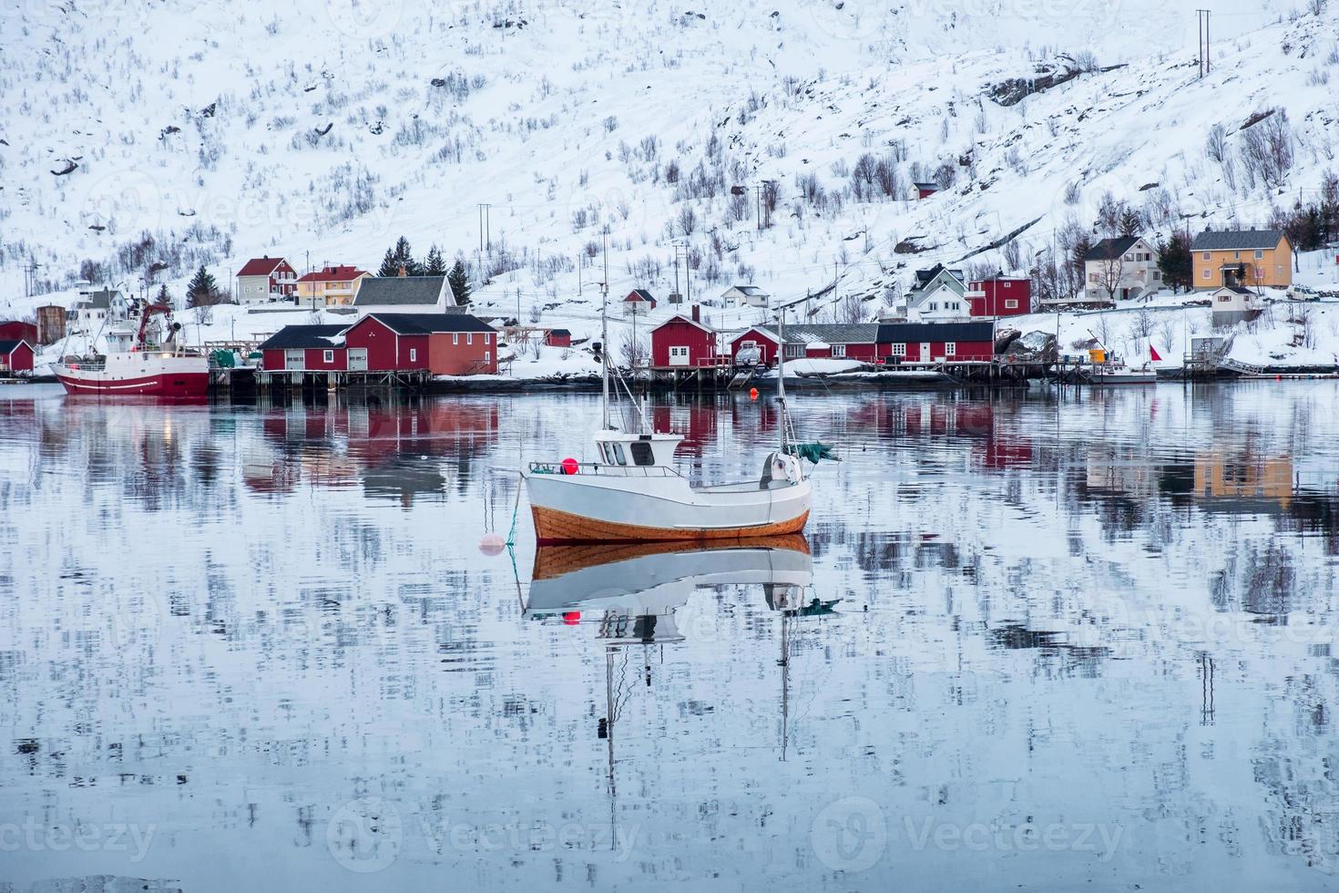 Fishing boat sailing reflection on arctic sea with scandinavian village photo