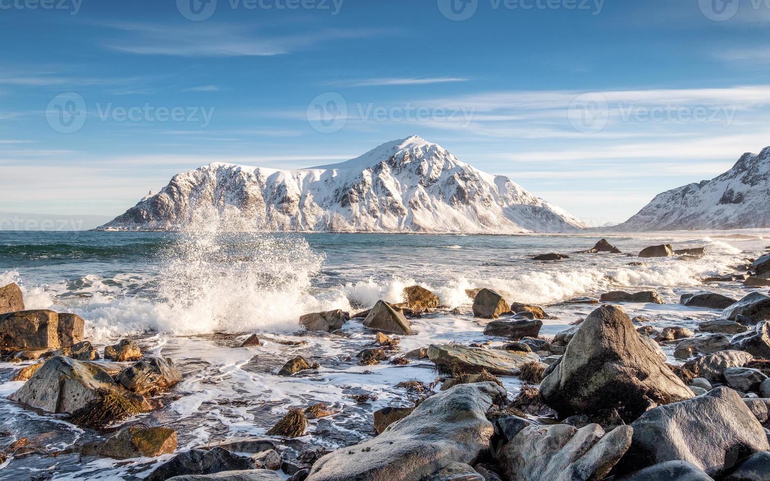 Arctic ocean wave hitting rocks with sunshine mountain photo