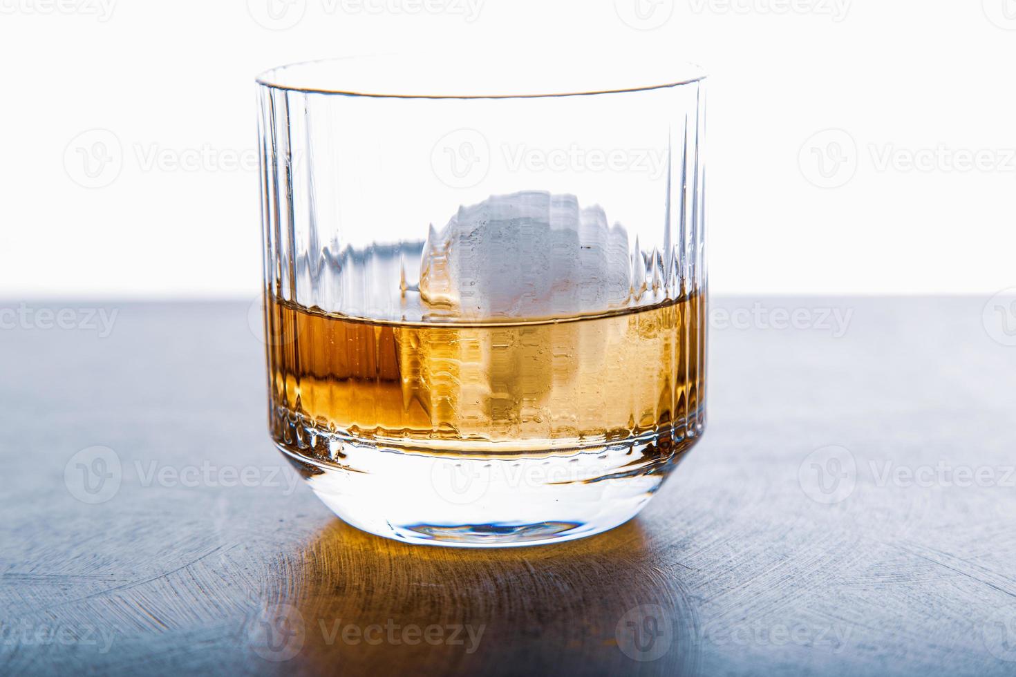 cubo de hielo en forma de esfera y vista de whisky de cerca desde el estudio. foto