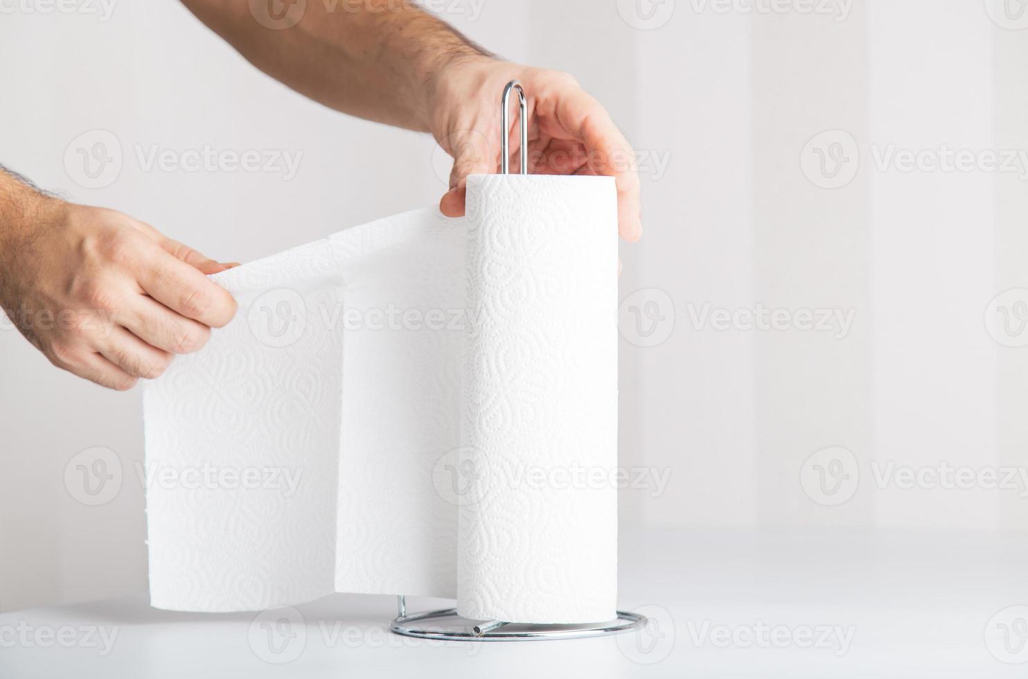 an anonymous hand is tearing off paper towel, hygiene concept copy space includes. photo