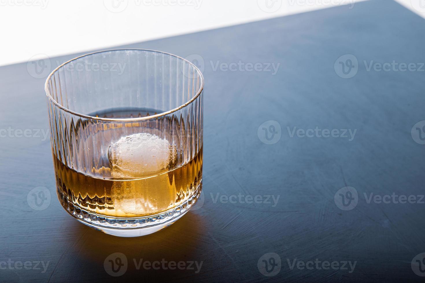 cubo de hielo en forma de esfera y vista de whisky de cerca desde el estudio. foto