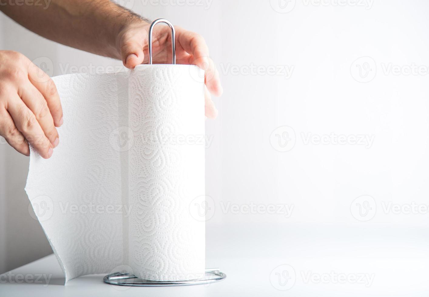 An anonymous hand is tearing off paper towel, hygiene concept copy space includes. photo