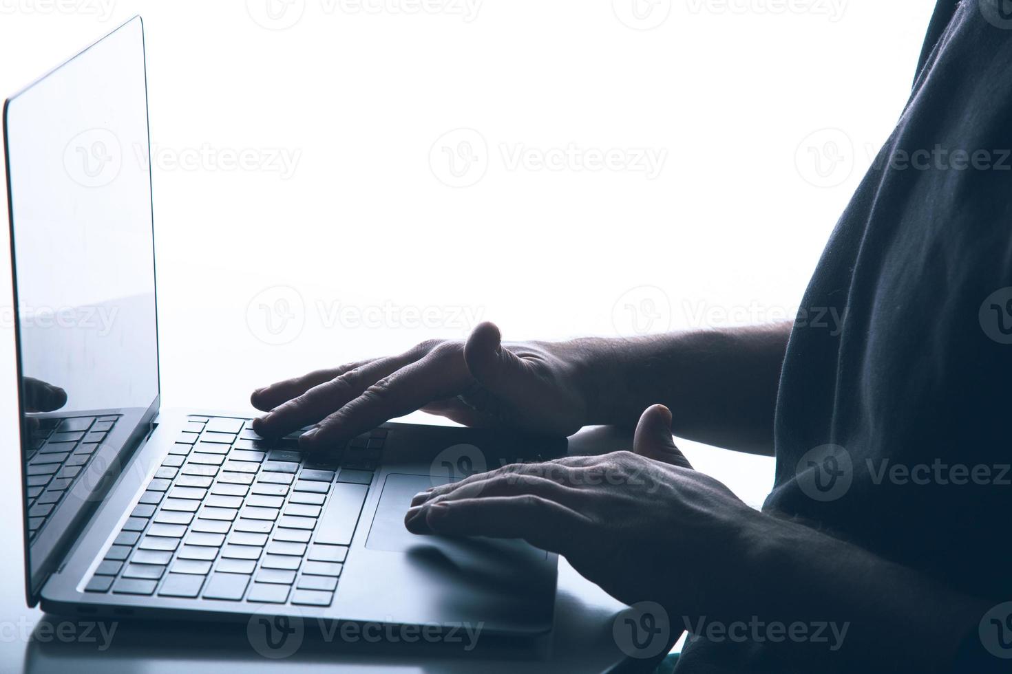 Cyber crime concept with copy space Anonymous man is using a laptop with reverse lighting photo
