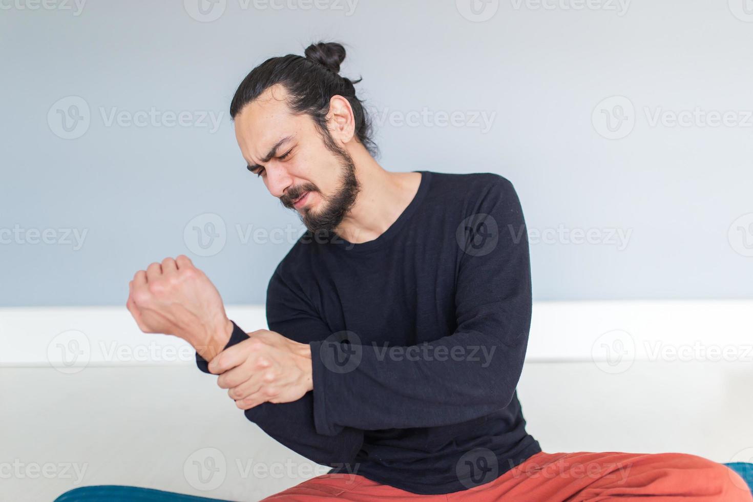 Young  athletic man is suffering pain from his wrist during workout or yoga photo