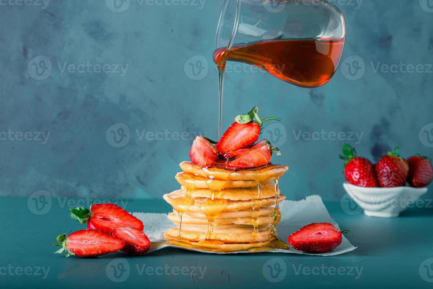 Syrup or honey is pouring to pancake stacks. Includes copy space. photo