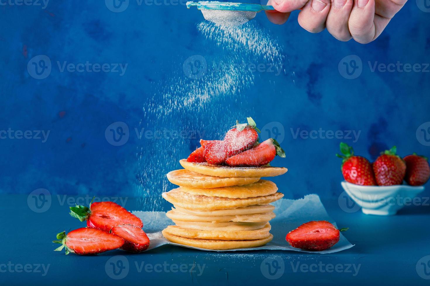 Anonymous hand is serving powder sugar to pancake stacks. Includes copy space. photo