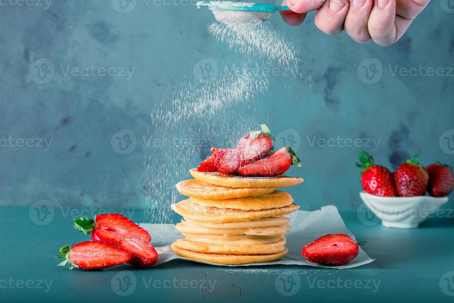 Anonymous hand is serving powder sugar to pancake stacks. Includes copy space. photo