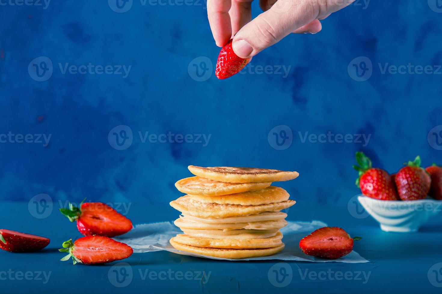 Anonymous hand is placing strawberry to pancake stacks. Includes copy space. photo