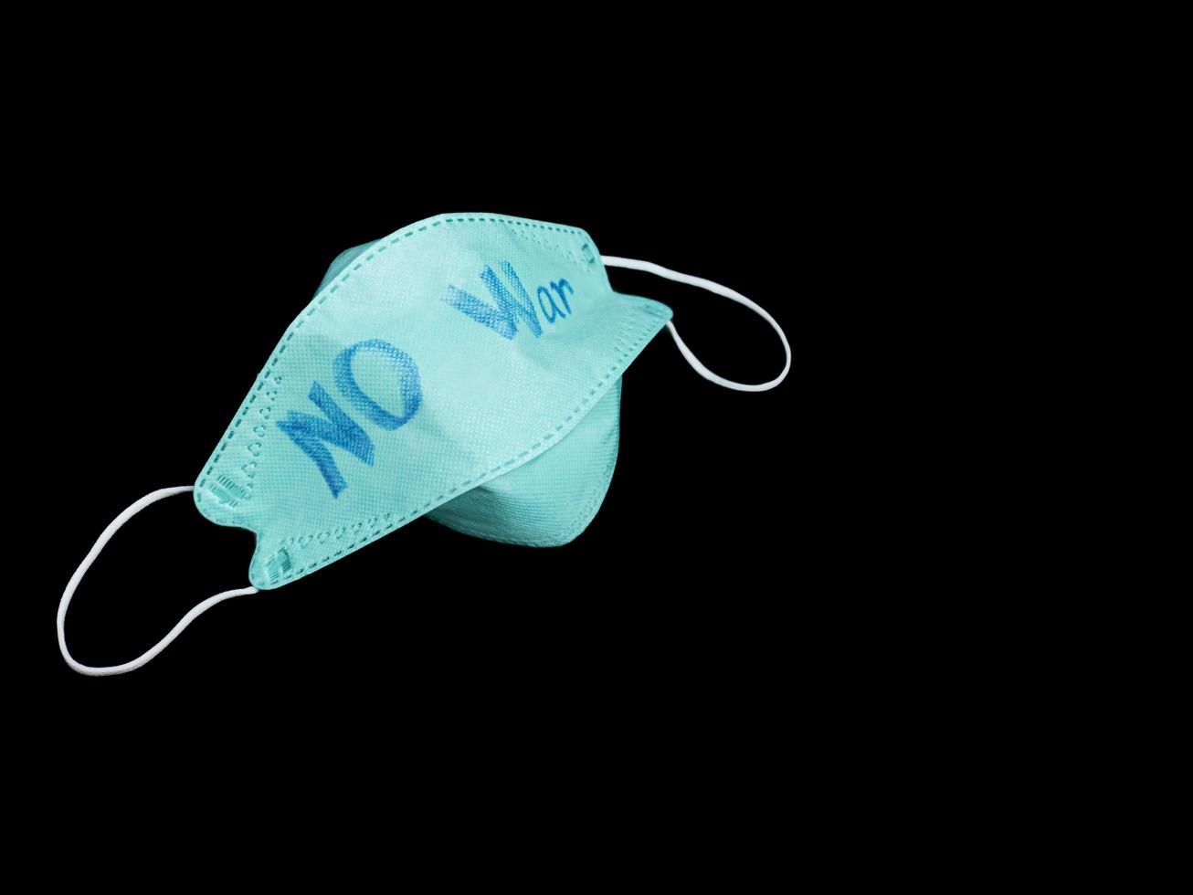 Masks that have already been used are discarded. in black background On the mask there is a handwritten note saying NO War. photo