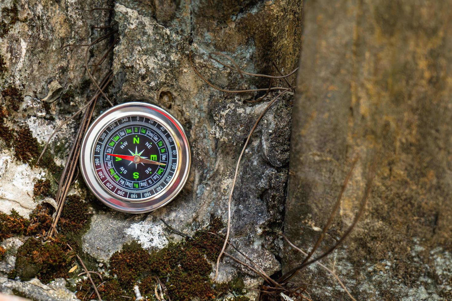 The compass is placed on the rock like a mountain, giving the mood of adventure travel on vacation. photo