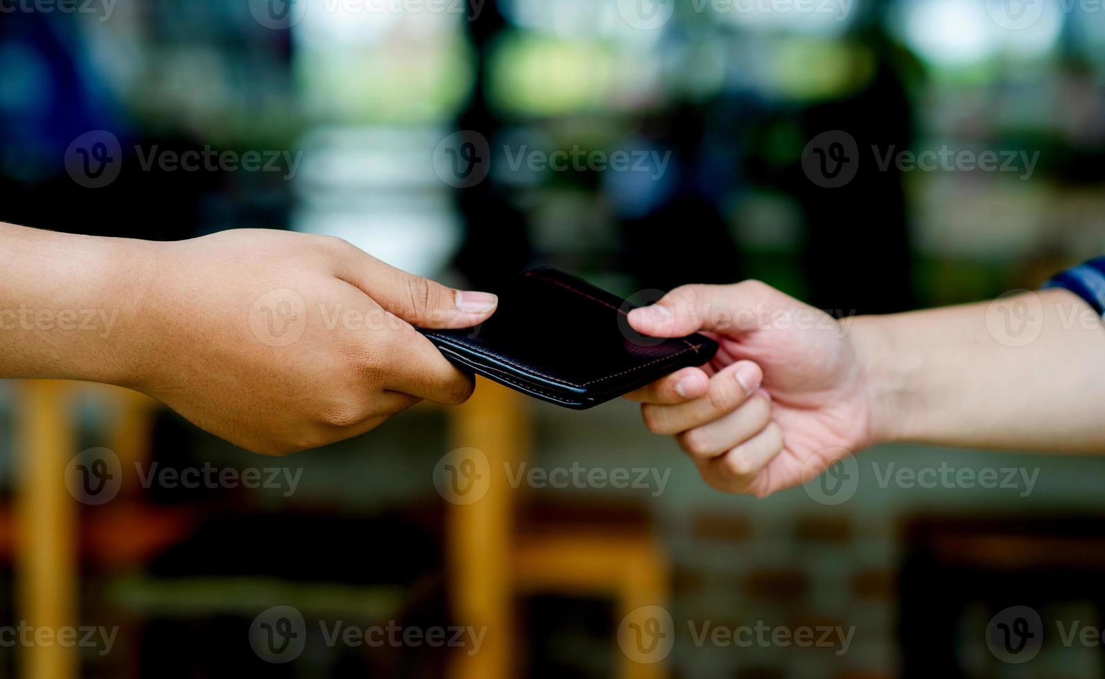 Two men's hands and purse hold the same purse. giving gifts to each other Collecting the wallet and returning it to the owner creating good deeds sharing one's own income photo